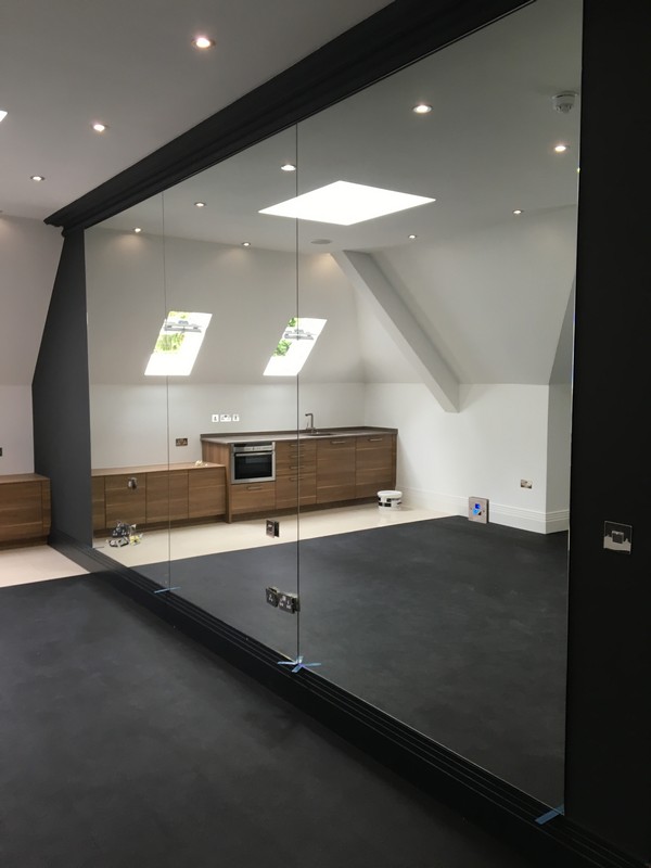 Frameless glass partition in loft conversion by New Malden glaziers