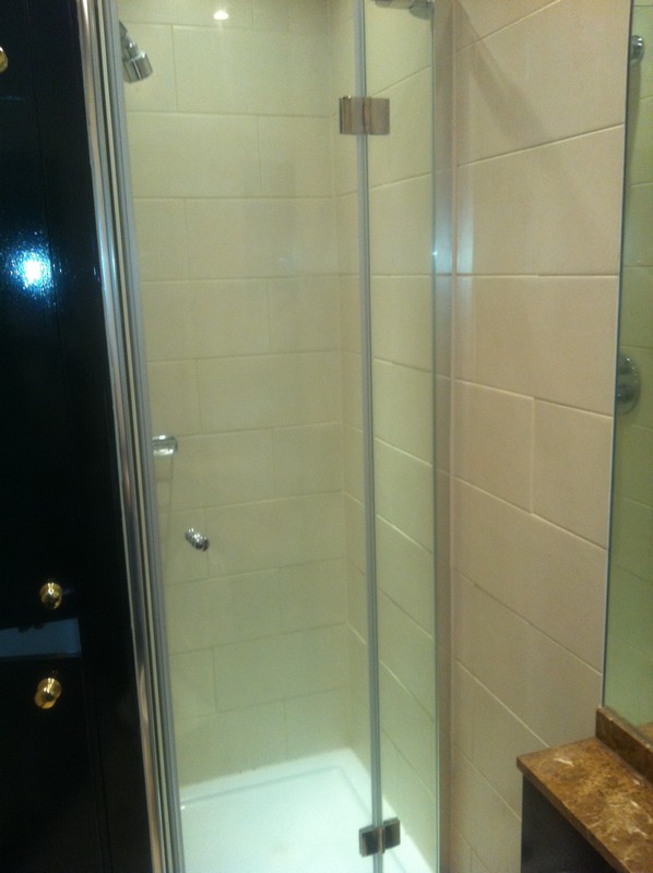 Frameless glass shower enclosure with chrome fittings in New Malden