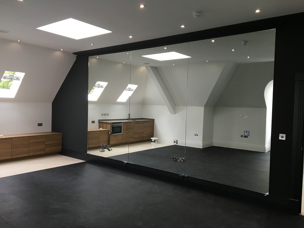 Frameless glass wall dividing loft conversion in New Malden